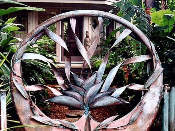 Decorative metal sculpture of dragonflies within a circular frame outdoors.