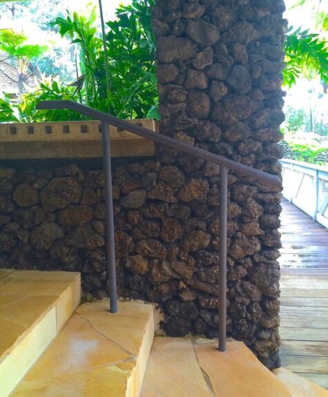 Stone wall with metal handrail beside outdoor stairs.