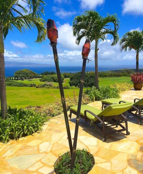 Tropical patio with tiki torches and lounge chairs overlooking the ocean.