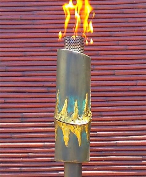 A bamboo torch with a burning flame against a wooden background.