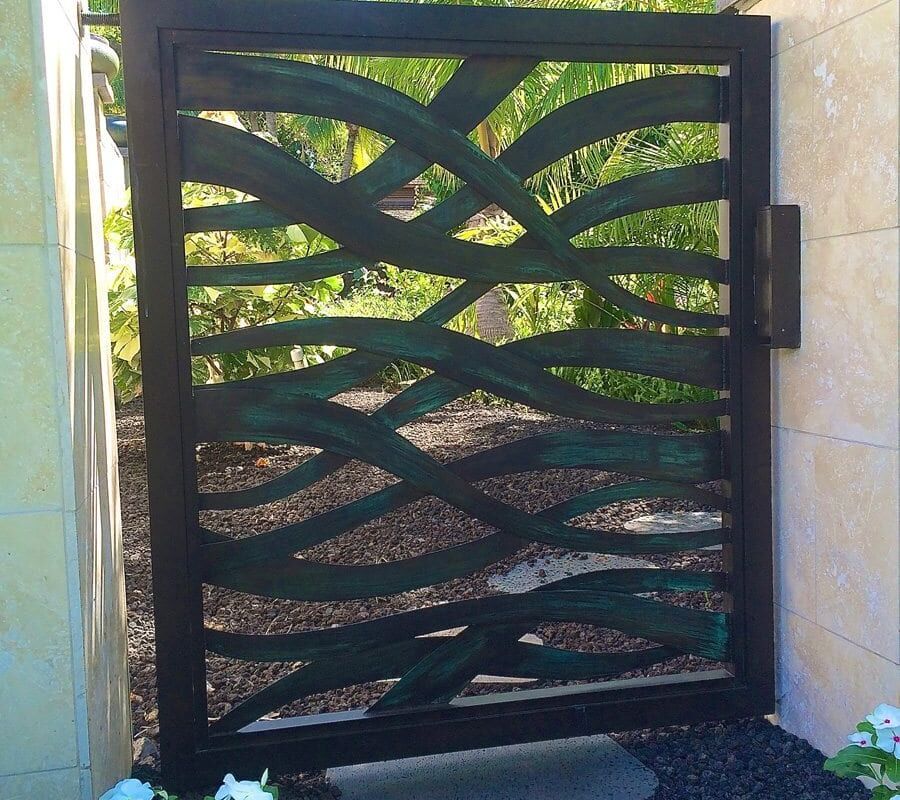 Decorative black metal garden gate with wave pattern.