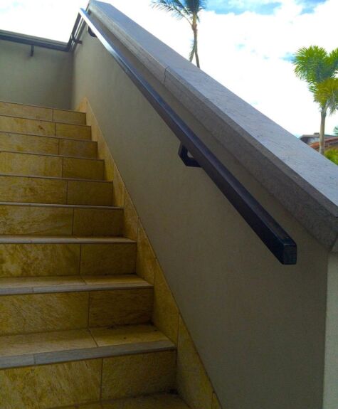 A staircase with a black handrail and a palm tree visible outside.