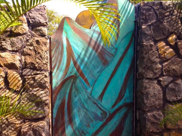 Colorful mural of a woman on a stone wall amidst greenery.