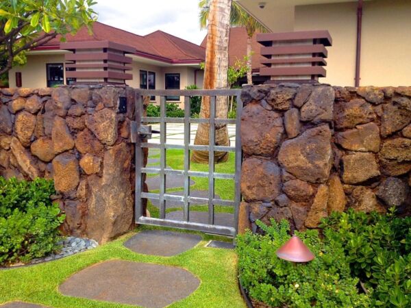 Stone wall with metal gate entrance to a garden.