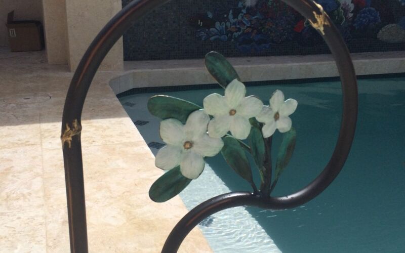 Decorative flower arrangement on a curved poolside rail.