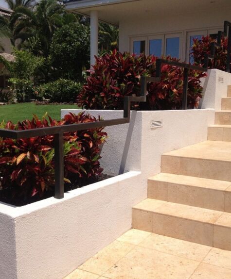 Outdoor stairs next to a white wall with red plants.