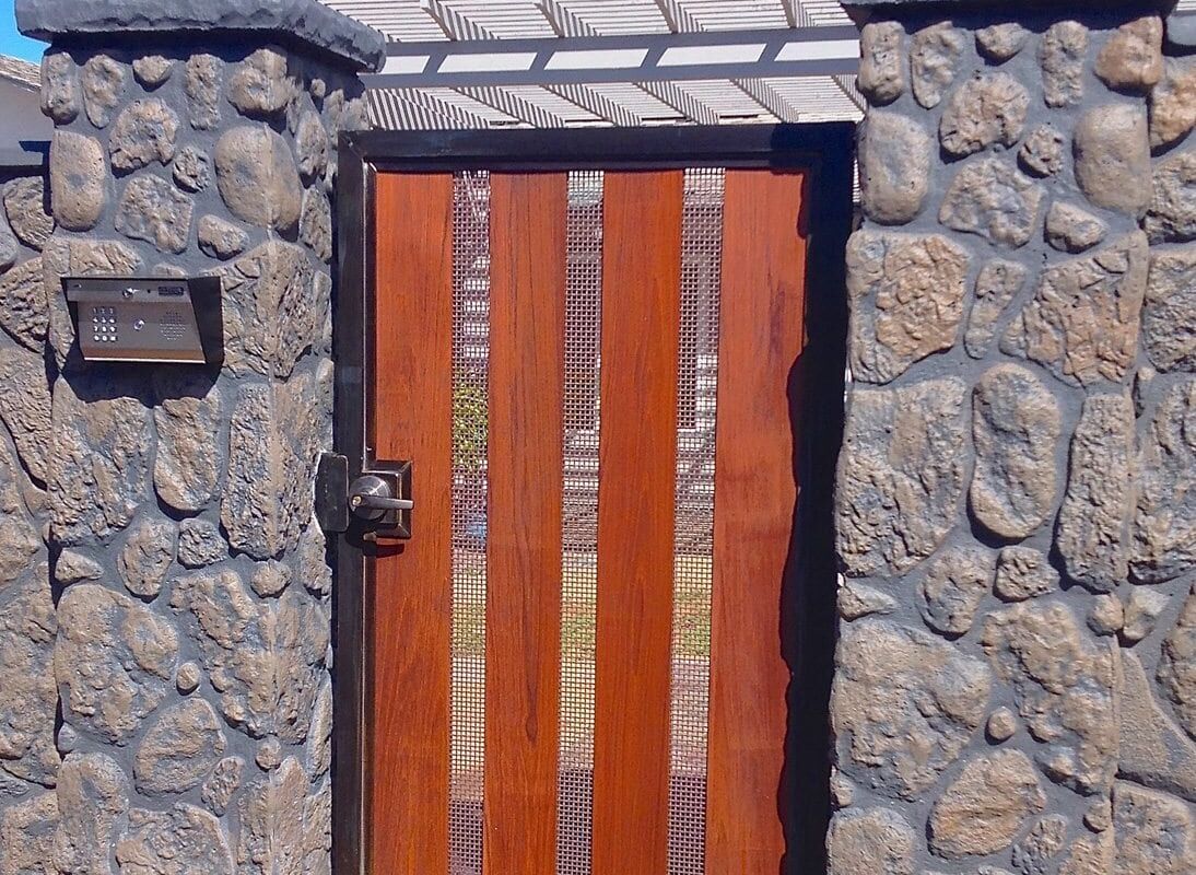 A wooden gate set in a stone wall under a blue sky.