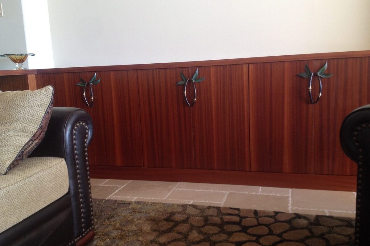Wood-paneled wall with ornate hooks and a leather armchair corner.