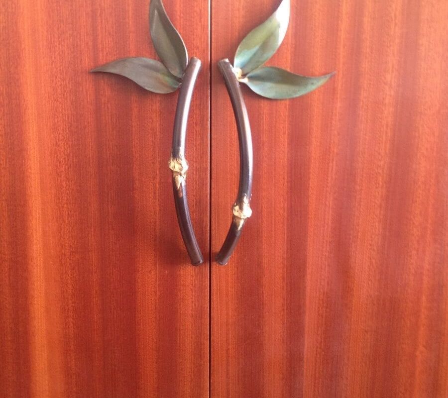Decorative door handles shaped like leaves on wooden doors.