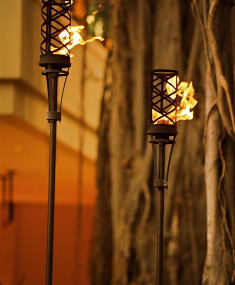 Warm glowing tiki torches lighting an outdoor space at night.