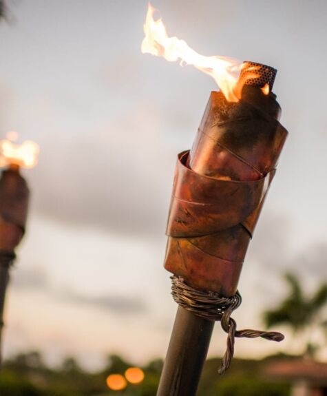 A tiki torch burning with a bright flame outdoors.