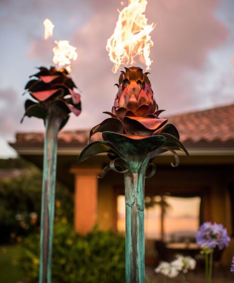 Two decorative torches with flames burning brightly outdoors.