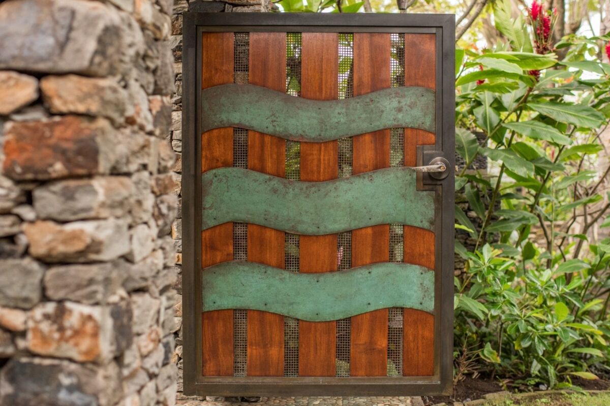 Decorative wooden door with green wavy metal accents outdoors.
