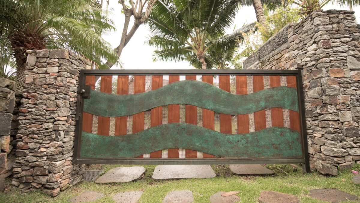 Decorative garden fence with a wavy green metal design and wooden panels.