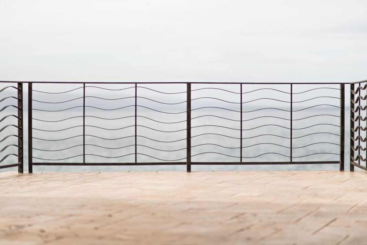 Wavy metal railing overlooking a foggy body of water.