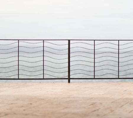 Wavy metal railing overlooking a foggy body of water.