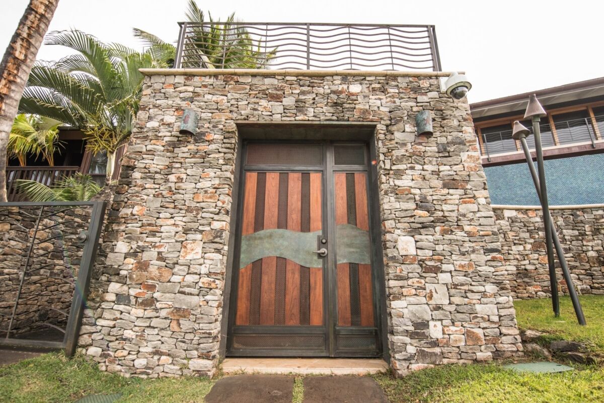 Rustic stone wall with large wooden double doors.