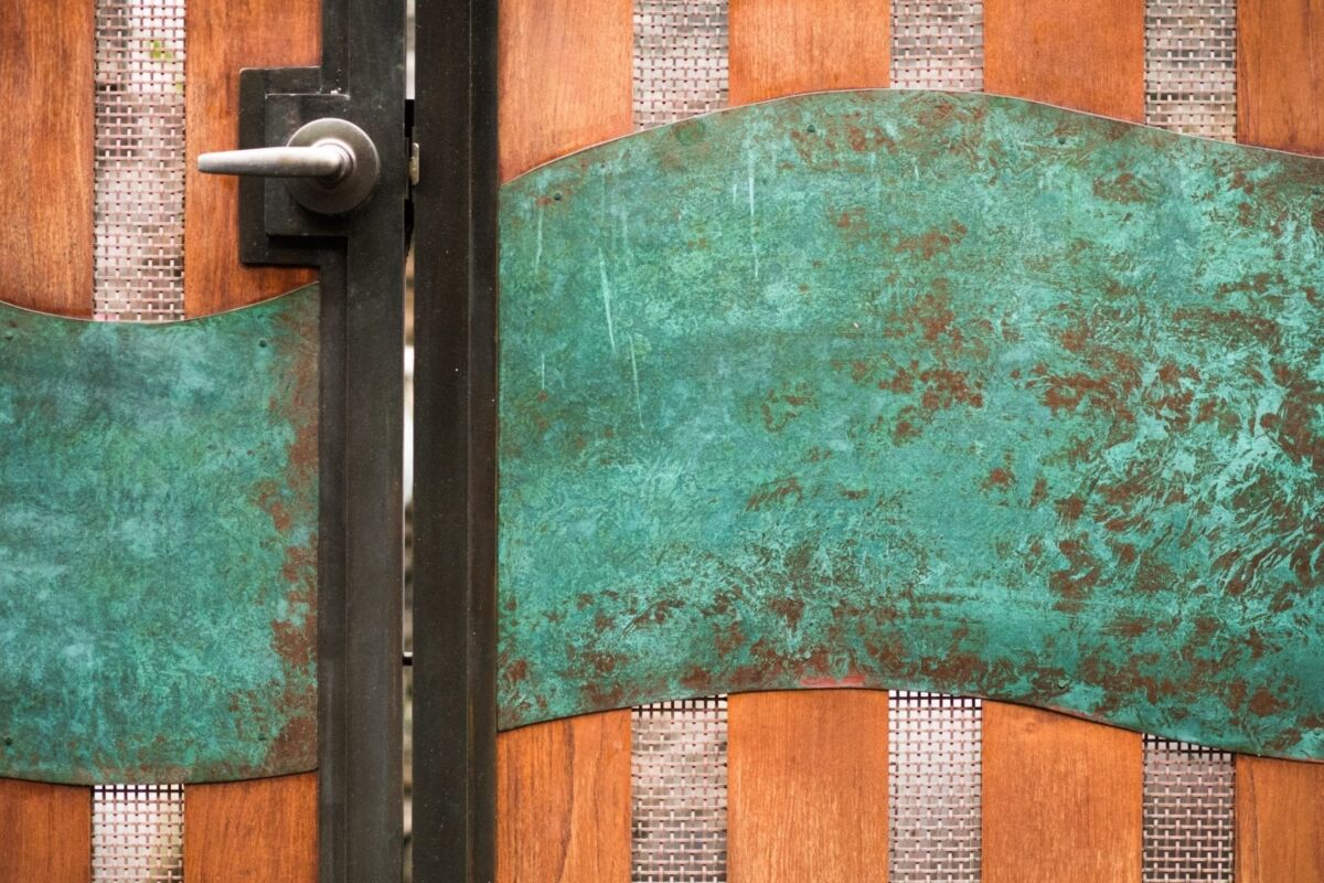 Close-up of a rustic door with peeling turquoise paint and a metal handle.