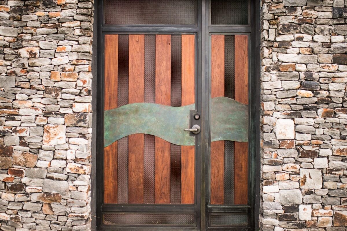 Rustic wooden door with metal accents set in a stone wall.