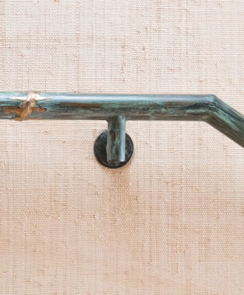 Close-up of a metal handrail mounted on a textured wall.