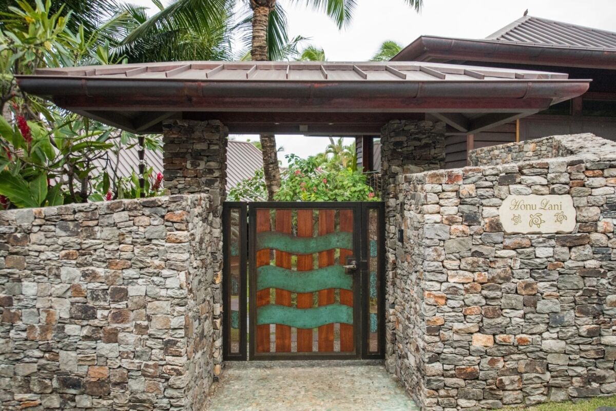 Rustic stone wall with a wooden gate and tiled roof.