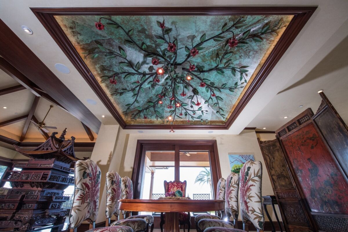 Elegant dining room with a painted floral ceiling and ornate chairs.