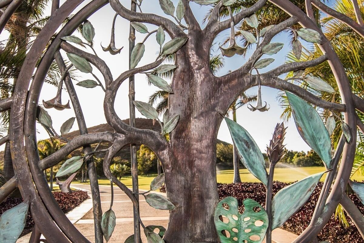 Intricate metal sculpture of a tree within circular frames in an outdoor setting.