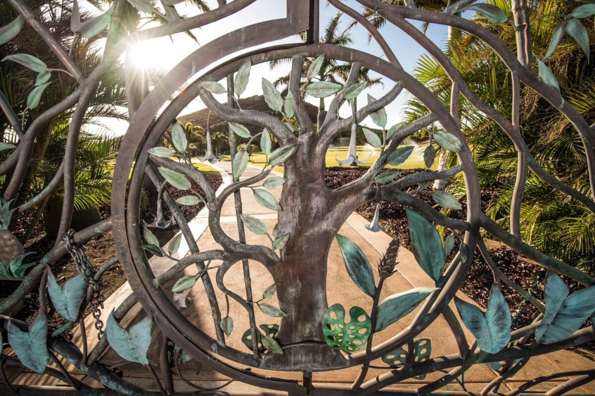Intricate metal sculpture of a tree with sunlight filtering through.