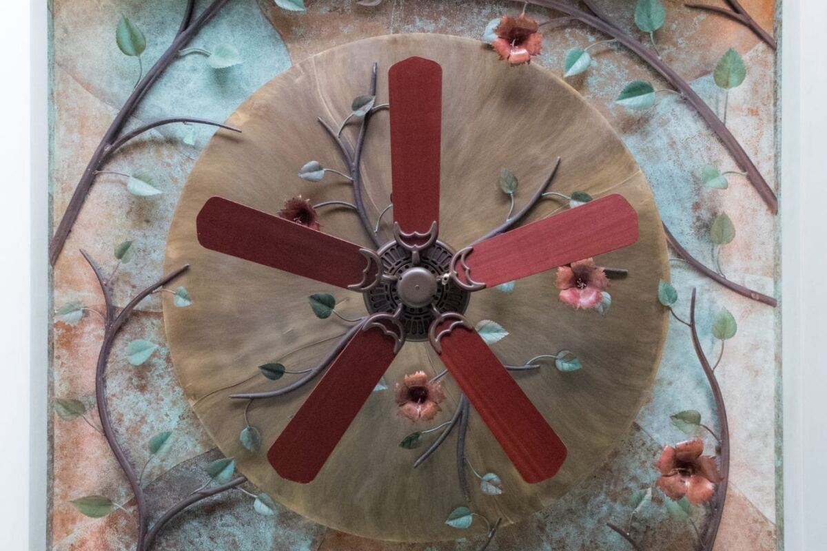 Decorative wall clock with a rustic, artistic design and floral accents.