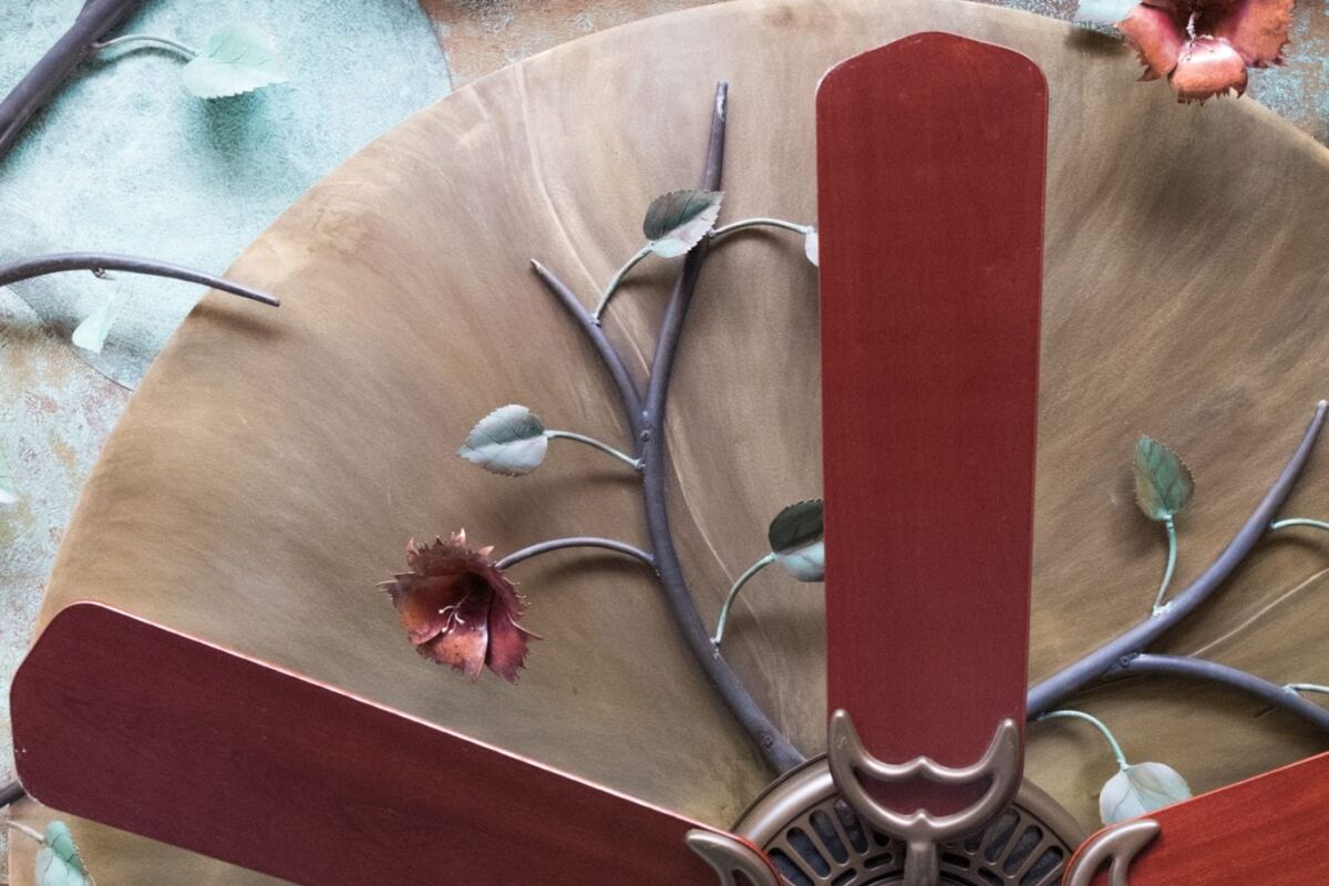 Close-up of a ceiling fan with wooden blades and a decorative base.