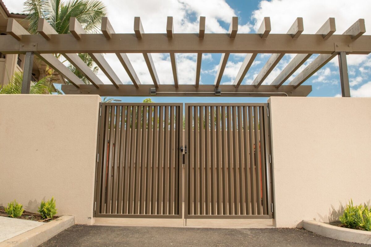 Modern metal gate with wooden slats under a pergola entrance.