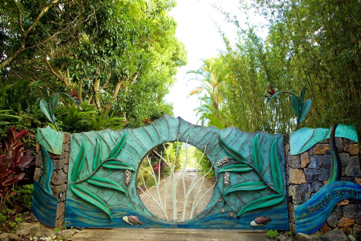 Decorative green gate with circular design amidst bamboo plants.