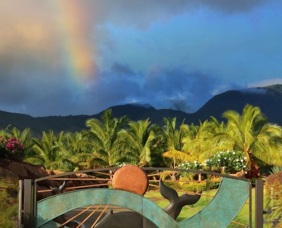 A vibrant rainbow arcs over lush greenery and mountains.