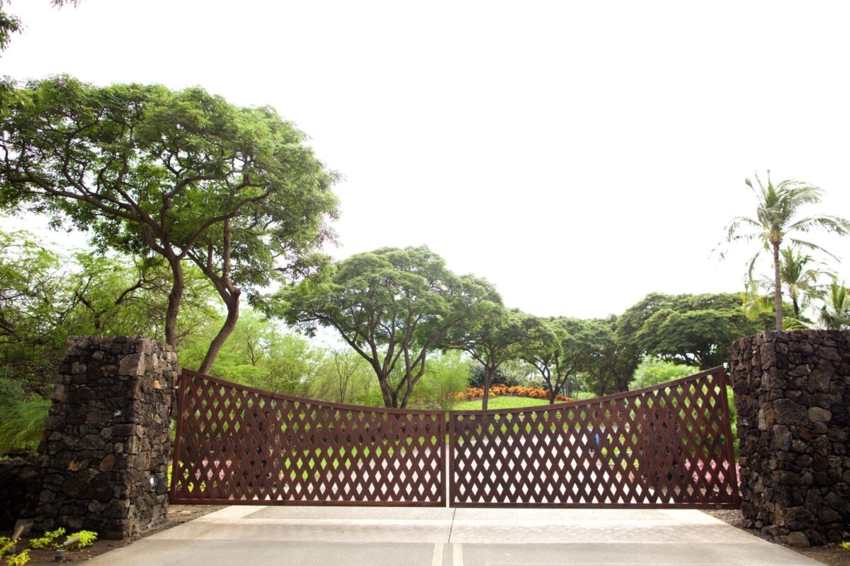 Ornate wooden gate with lush green trees in the background.
