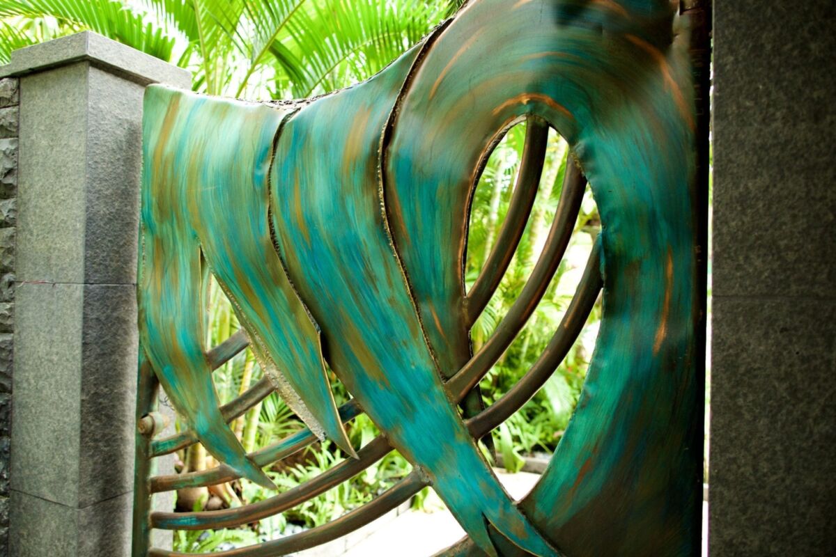 Close-up of a large, curved green sculpture with rib-like design outdoors.