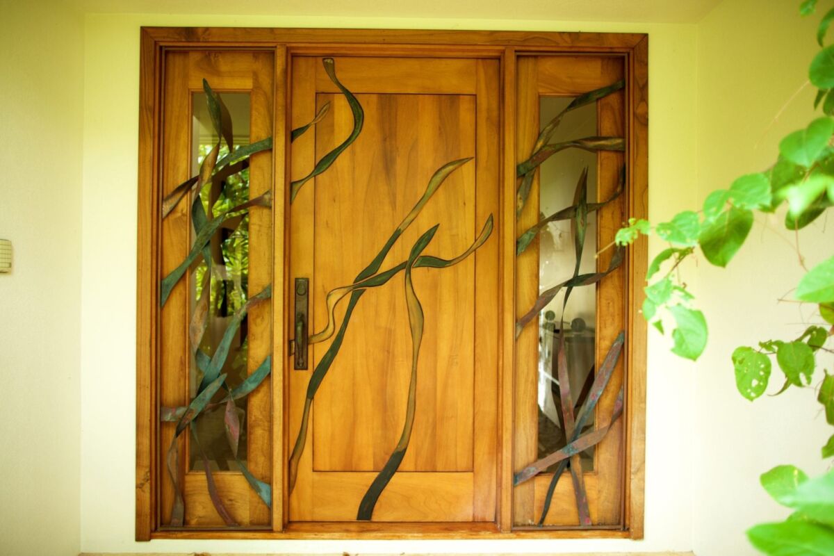 Wooden window with artistic vine design and yellow wall.