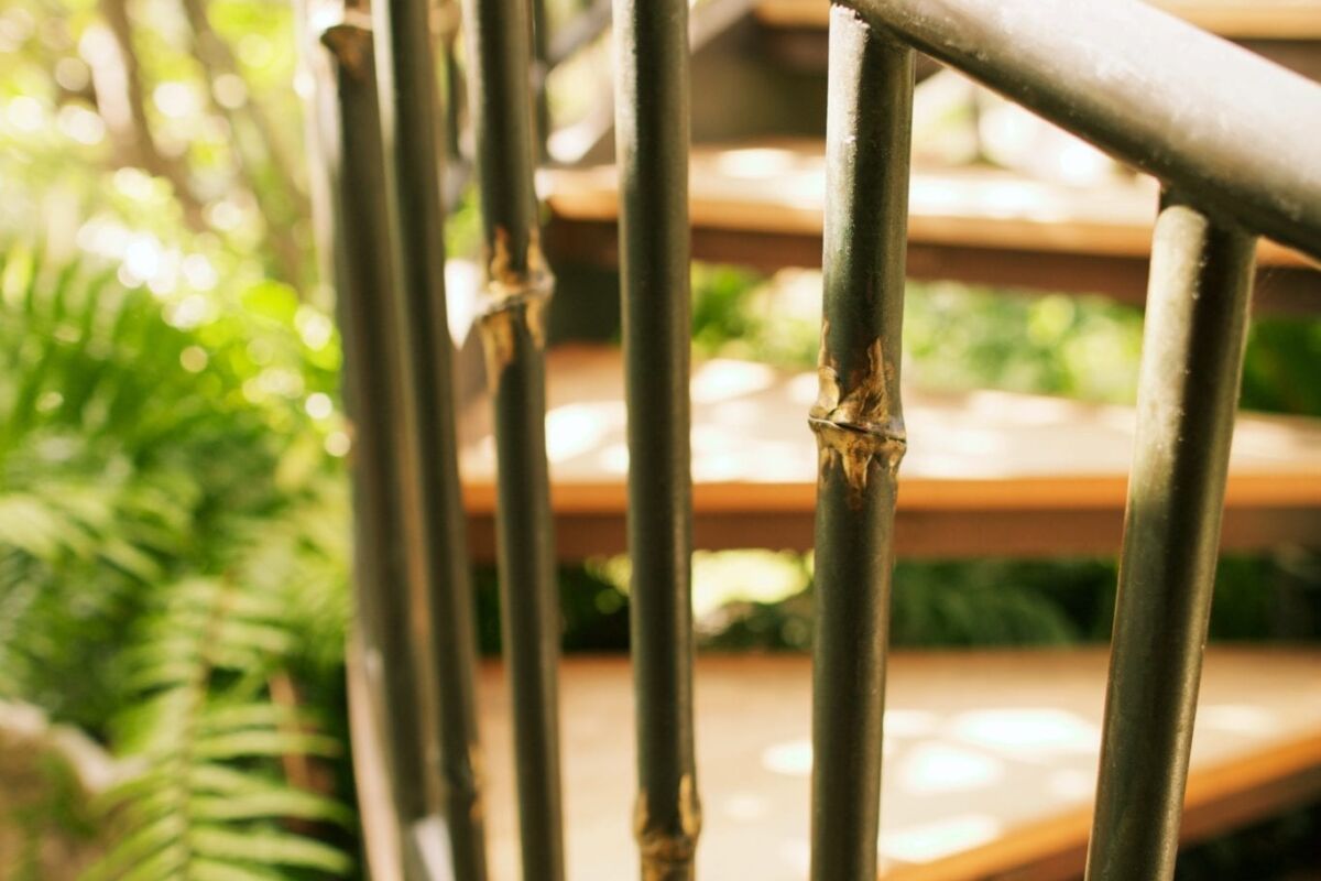 Close-up of a spiral staircase railing surrounded by greenery.