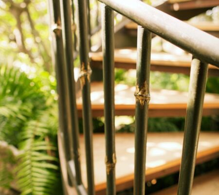 Close-up of a spiral staircase railing surrounded by greenery.