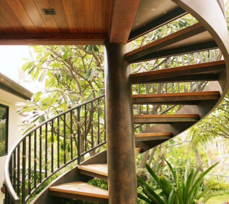 Elegant outdoor spiral staircase surrounded by lush greenery.