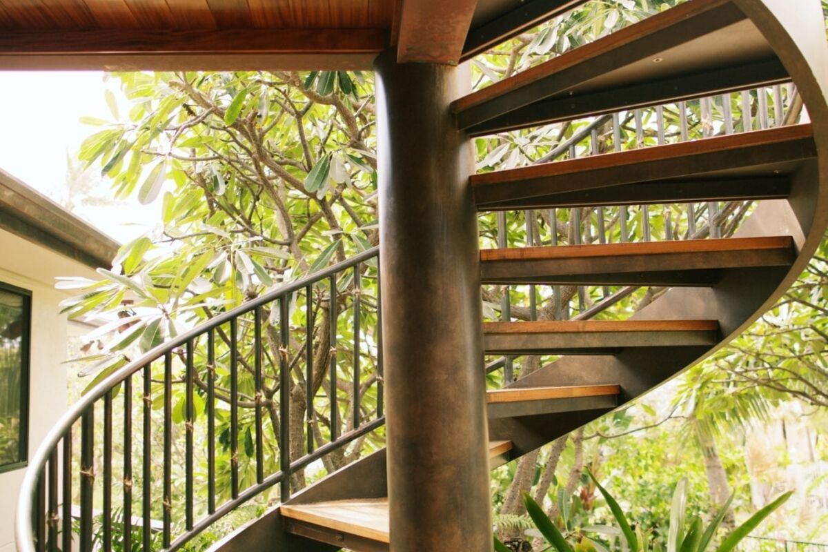 Elegant outdoor spiral staircase surrounded by lush greenery.
