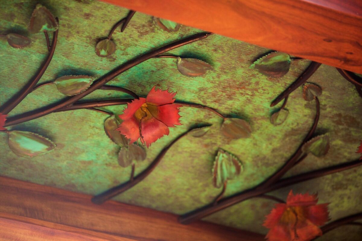 Close-up of a floral ceiling design with vibrant red flowers and green leaves.