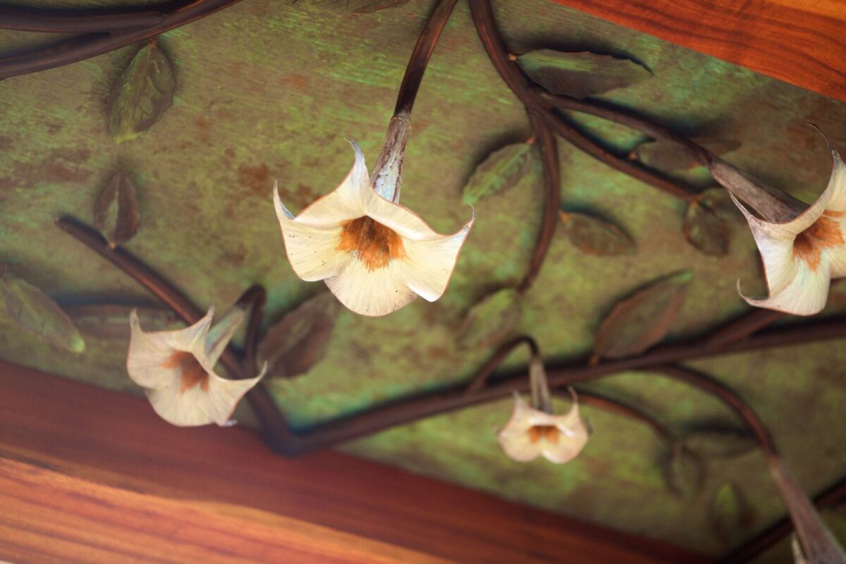 Decorative wall with trumpet-shaped flowers and twisted branches.