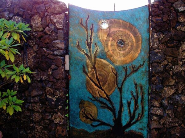 Artistic mural of leaves and a spiral shell on a stone wall.