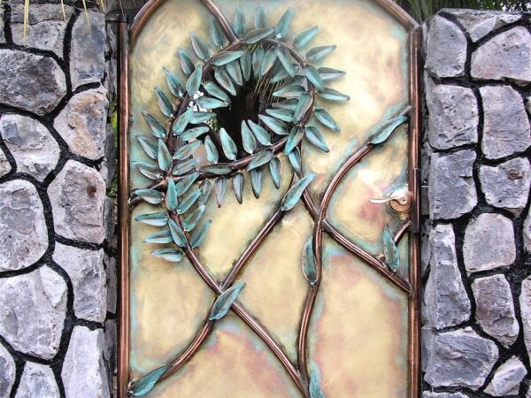 A stained glass panel with a sunflower design set in a stone wall.