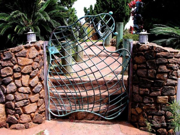 Artistic metal gate with a spiral design at garden entrance.