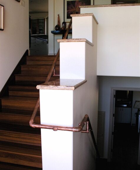 A staircase with wooden steps and copper handrails inside a house.