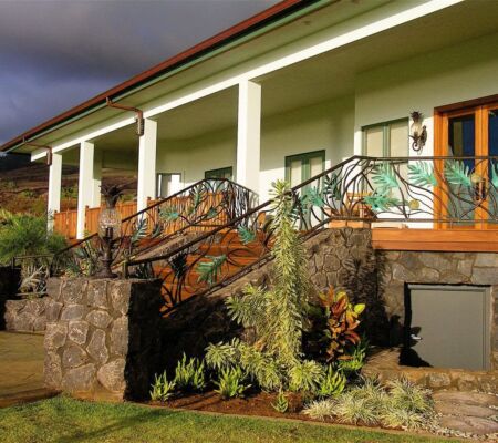 Cozy house porch with wooden railing and stone steps surrounded by greenery.