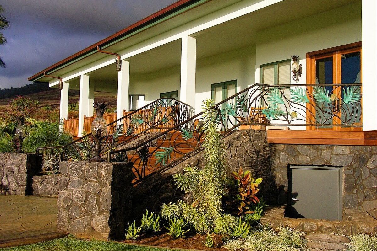 Cozy house porch with wooden railing and stone steps surrounded by greenery.
