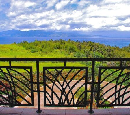 Scenic balcony view overlooking lush greenery and a distant blue horizon.