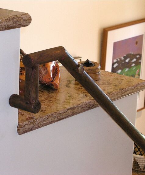 A rustic handrail with wooden handles attached to a staircase.